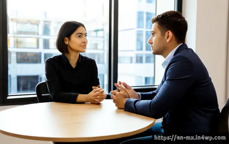 비폭력 커뮤니케이션과 신뢰 구축 - Photorealistic workplace conversation between two diverse colleagues seated across a small round tab...